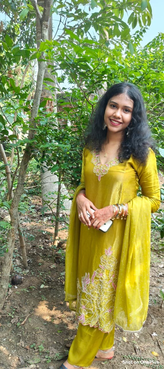 Avuu smiling outdoors in a yellow outfit